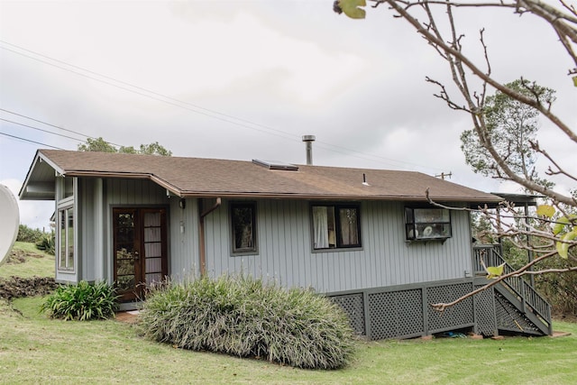rear view of house with a shingled roof and a yard