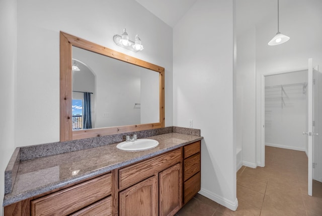 full bathroom with tile patterned floors, vaulted ceiling, baseboards, a spacious closet, and vanity