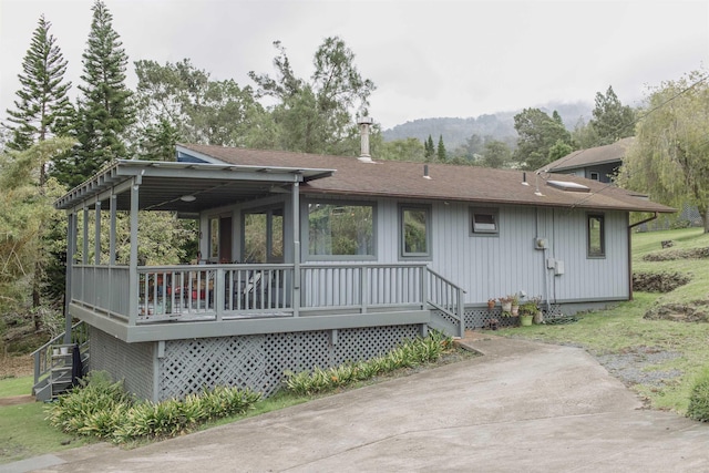 exterior space with roof with shingles, a deck with mountain view, and stairway