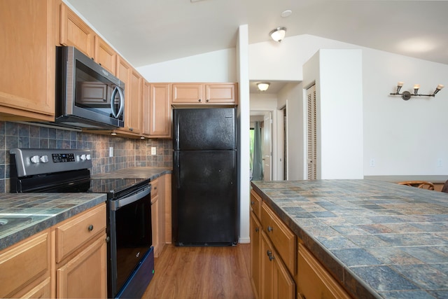 kitchen with light brown cabinets, lofted ceiling, backsplash, black appliances, and dark hardwood / wood-style flooring