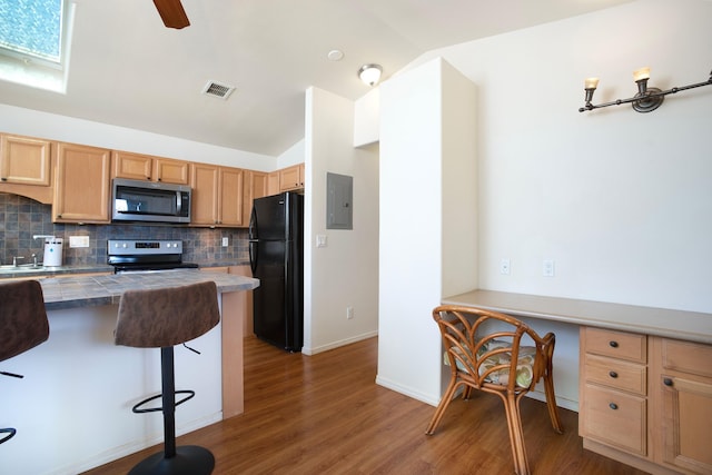 kitchen with lofted ceiling with skylight, backsplash, electric panel, a kitchen breakfast bar, and stainless steel appliances