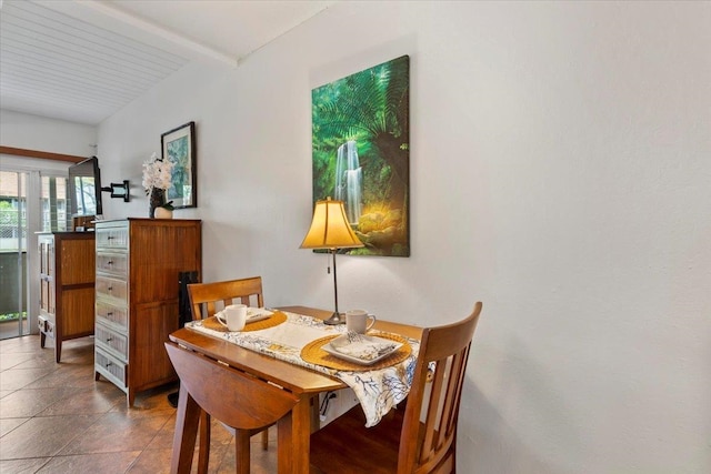 tiled dining room featuring beamed ceiling