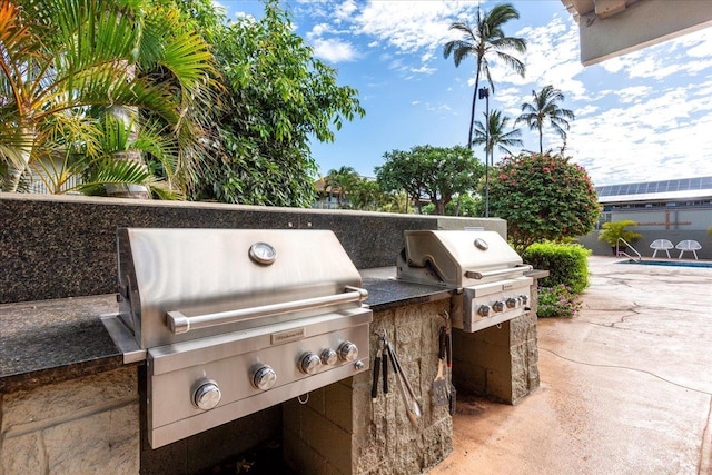 view of patio / terrace featuring a swimming pool, a grill, and exterior kitchen