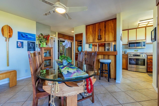 dining area featuring ceiling fan, baseboards, and light tile patterned flooring