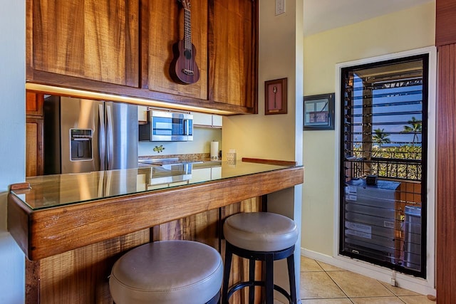 bar with appliances with stainless steel finishes, baseboards, and light tile patterned floors