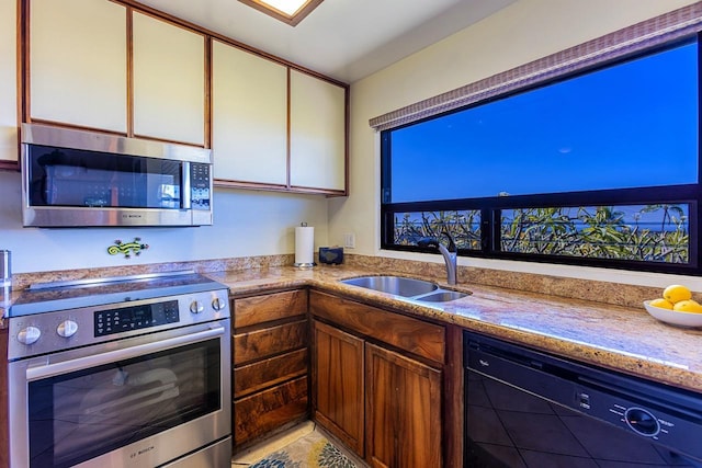 kitchen featuring white cabinets, light stone countertops, stainless steel appliances, and a sink