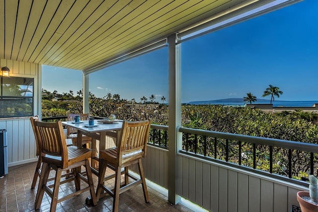 balcony featuring a sunroom and outdoor dining area