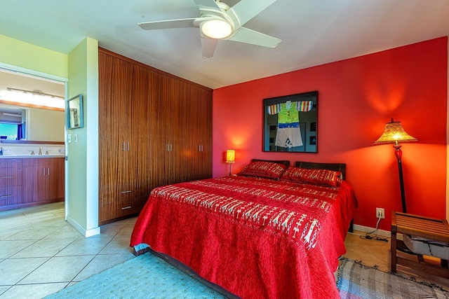 bedroom with light tile patterned floors, ceiling fan, ensuite bath, and a sink