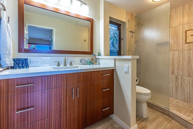 bathroom with tiled shower, vanity, and toilet