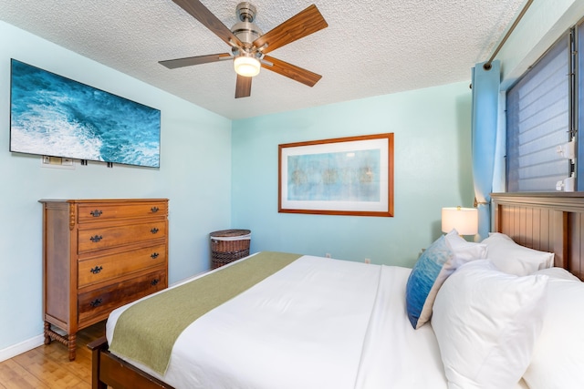 bedroom with hardwood / wood-style floors, ceiling fan, and a textured ceiling