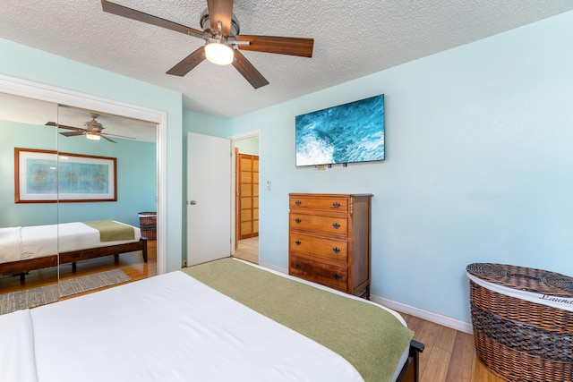 bedroom with a textured ceiling, light wood-type flooring, and ceiling fan