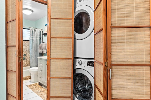 laundry room with light tile patterned floors and stacked washing maching and dryer