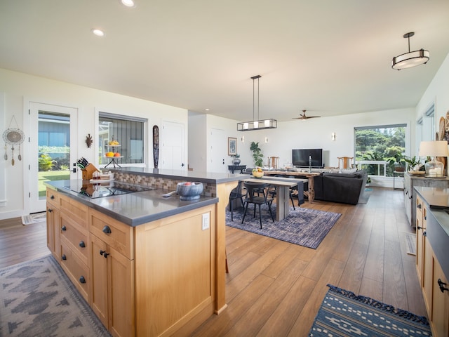 kitchen with black electric cooktop, decorative light fixtures, dark wood-type flooring, and a kitchen island