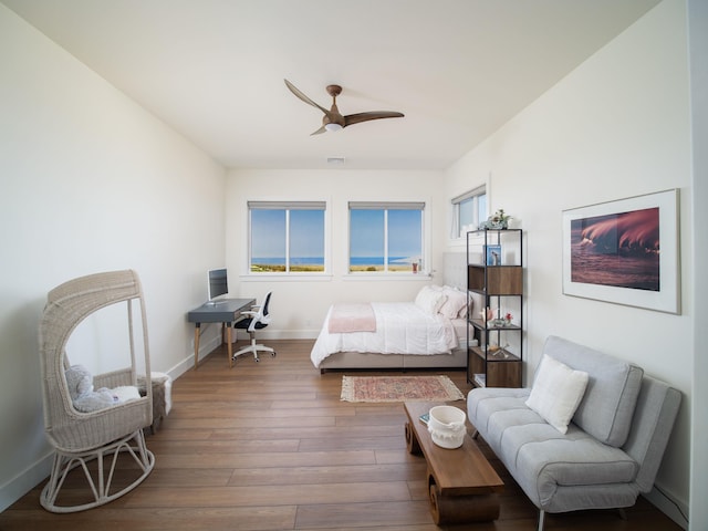 bedroom with multiple windows, wood-type flooring, and ceiling fan