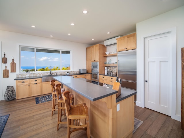 kitchen featuring sink, a kitchen breakfast bar, stainless steel appliances, a kitchen island, and an AC wall unit