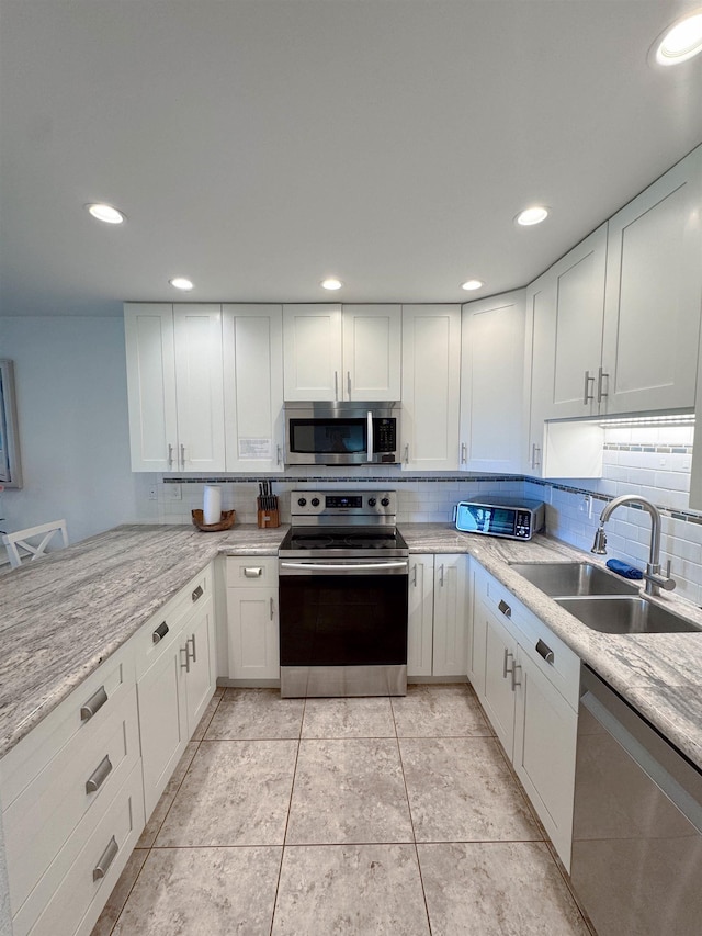 kitchen featuring backsplash, stainless steel appliances, white cabinets, and a sink
