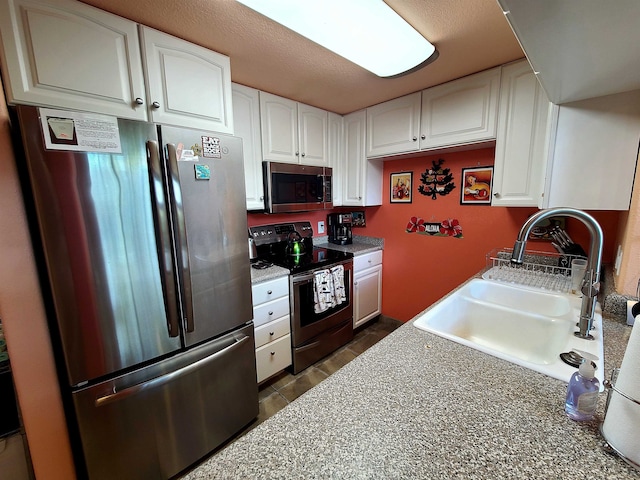 kitchen featuring a textured ceiling, white cabinetry, sink, and appliances with stainless steel finishes