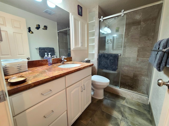 bathroom featuring tile patterned floors, a shower with door, vanity, and toilet