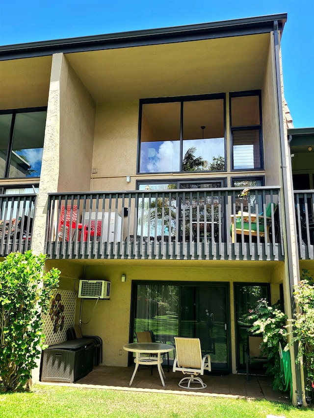 rear view of house featuring a wall mounted air conditioner and a balcony