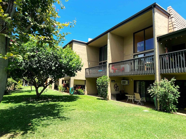 back of property with a wall mounted AC and a lawn