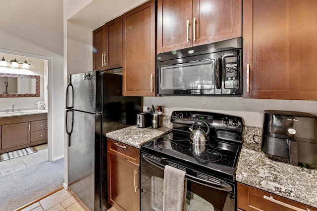 kitchen with light carpet, black appliances, sink, and light stone countertops