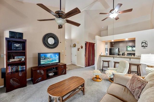 carpeted living room with ceiling fan and high vaulted ceiling