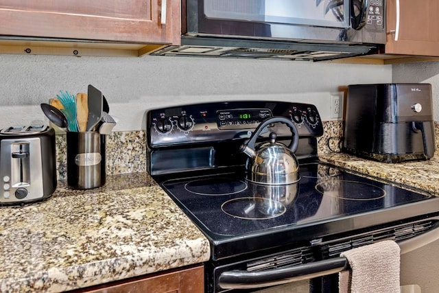 kitchen featuring decorative backsplash, light stone countertops, and black appliances