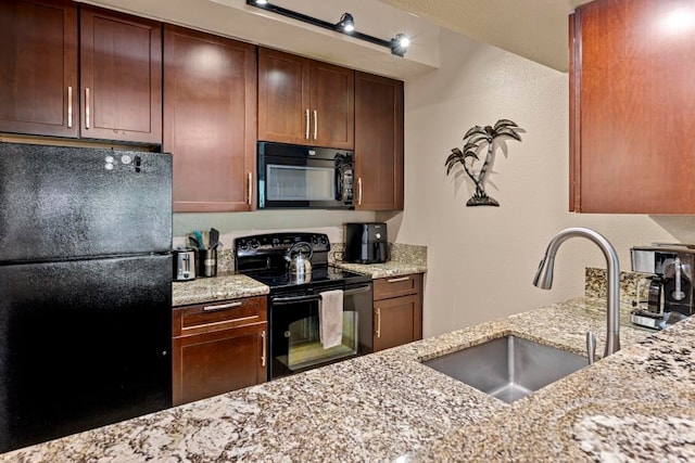 kitchen featuring light stone countertops, black appliances, and sink