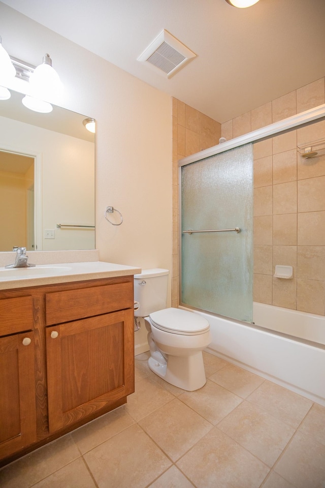 full bathroom with tile patterned floors, bath / shower combo with glass door, vanity, and toilet