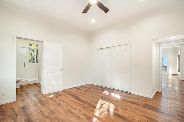 unfurnished bedroom featuring hardwood / wood-style floors, a closet, ensuite bath, and ceiling fan