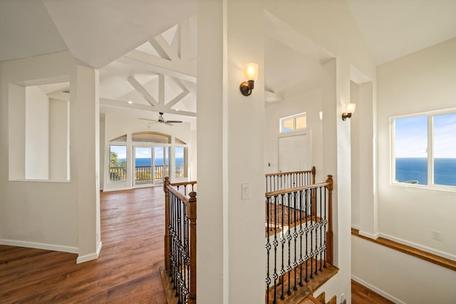 hallway featuring a water view, dark wood-type flooring, and lofted ceiling