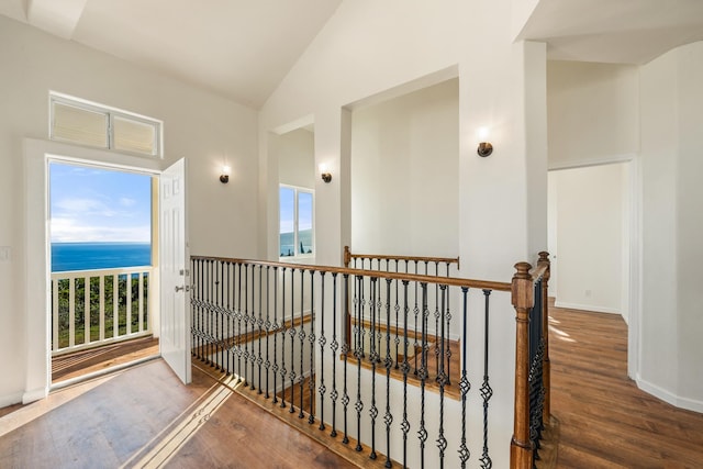 hallway with dark hardwood / wood-style flooring, a water view, and vaulted ceiling