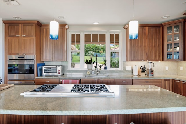 2335 Hihimanu St Unit 117, Kihei, HI 96753 - kitchen featuring stainless steel appliances, decorative backsplash, glass insert cabinets, hanging light fixtures, and light stone counters