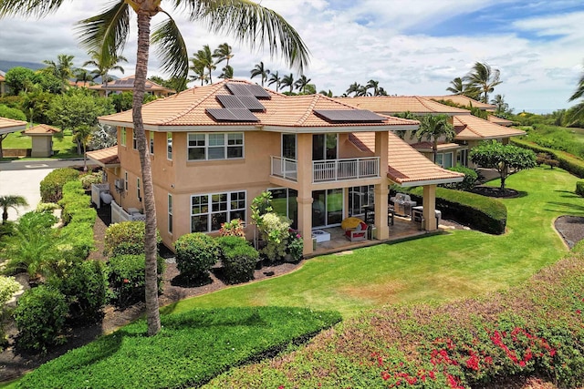 2335 Hihimanu St Unit 117, Kihei, HI 96753 - rear view of house featuring a balcony, roof mounted solar panels, a patio area, and a yard