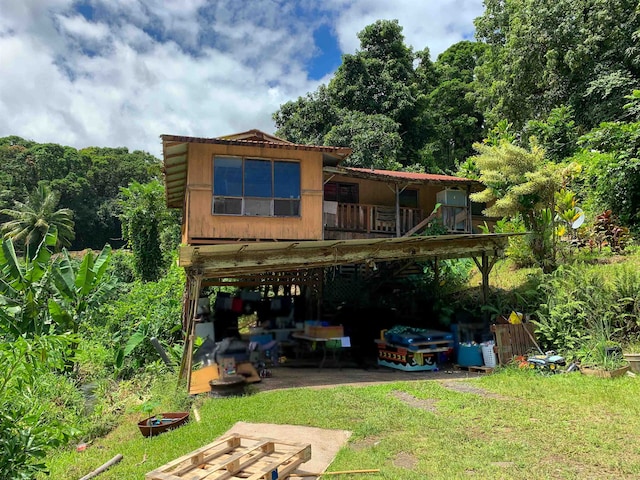 rear view of house featuring a carport and a lawn