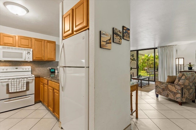 kitchen featuring dark stone counters, tasteful backsplash, white appliances, and light tile floors