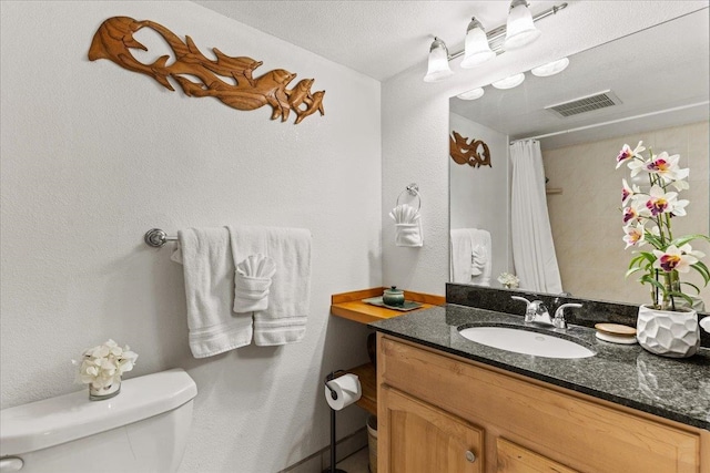 bathroom with a textured ceiling, toilet, and vanity