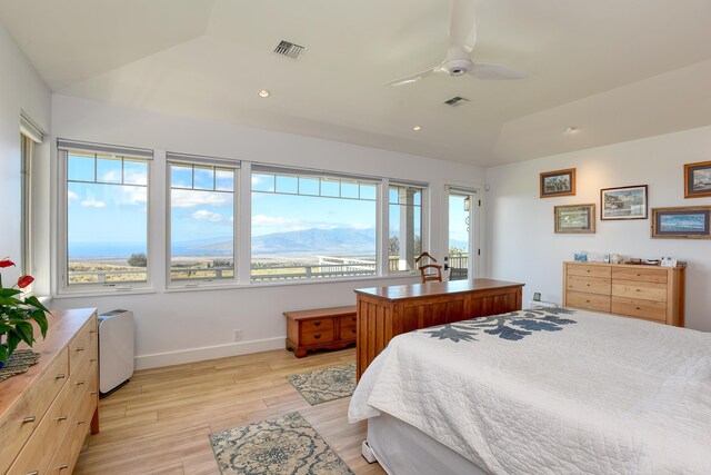 bedroom with lofted ceiling, a mountain view, ceiling fan, and light wood-type flooring