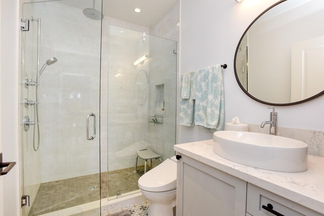 bathroom featuring walk in shower, vanity, and toilet