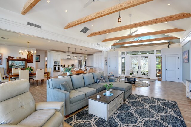 living room with beam ceiling, french doors, a chandelier, and light wood-type flooring