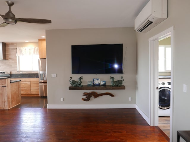 living room with ceiling fan, dark hardwood / wood-style floors, a wall unit AC, and washer / clothes dryer