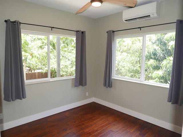 empty room with dark hardwood / wood-style flooring, plenty of natural light, a wall mounted AC, and ceiling fan