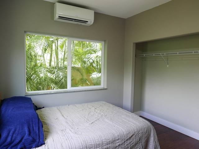 bedroom with a wall unit AC, a closet, and wood-type flooring