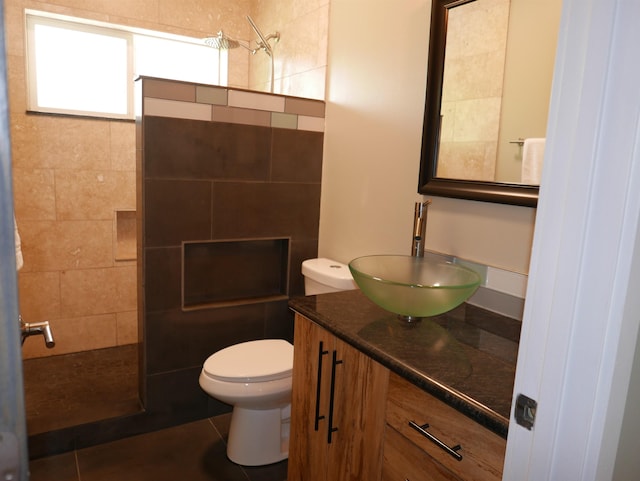 bathroom featuring tile patterned flooring, a tile shower, vanity, and toilet