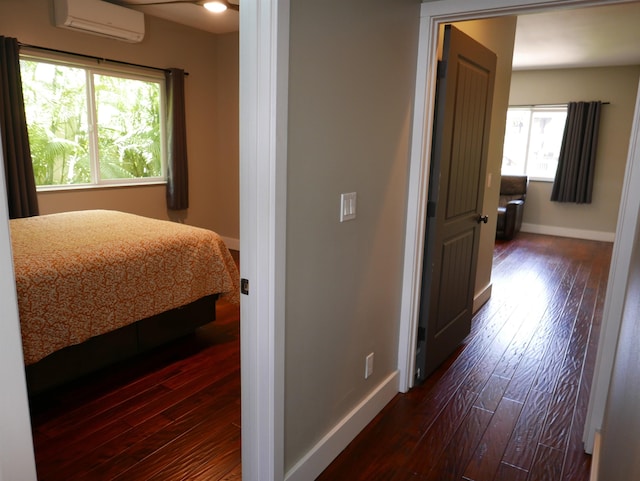 bedroom with an AC wall unit and dark wood-type flooring