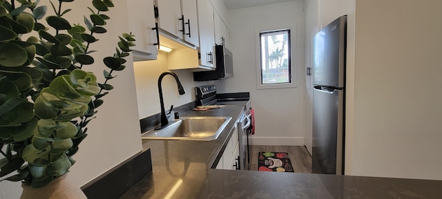 kitchen featuring white cabinetry, sink, wood-type flooring, and appliances with stainless steel finishes