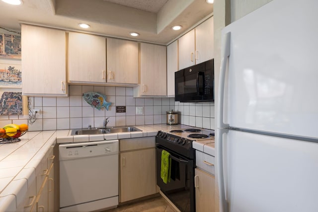 kitchen with tasteful backsplash, sink, tile countertops, and black appliances