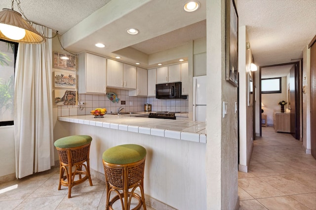 kitchen with tasteful backsplash, tile countertops, a textured ceiling, white refrigerator, and kitchen peninsula