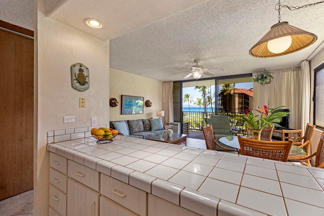 living room with ceiling fan and a textured ceiling