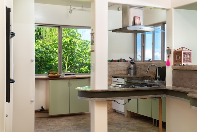 kitchen with island exhaust hood, decorative backsplash, green cabinetry, and plenty of natural light